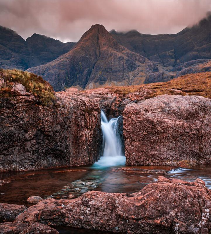 dramatic rock formations at sunrise in a mountainous landscape with three spires in the foreground
